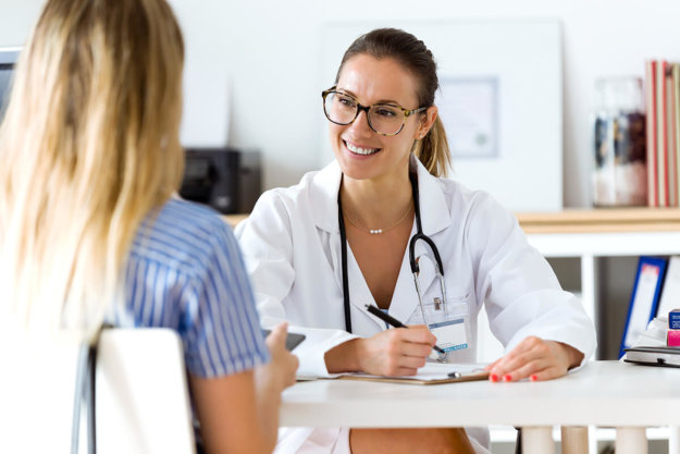female doctor smiles while taking notes and talking to patient at a womens alcohol rehab center arizona
